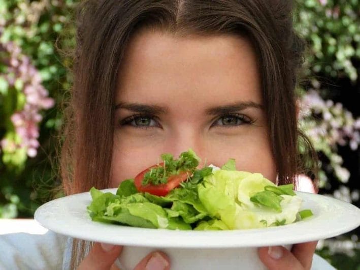 die Frau hält einen Teller mit Salat