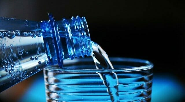  Wasser aus einer Flasche in ein Glas gegossen