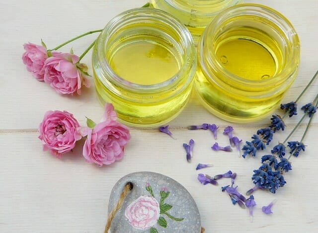  Kosmetische Öle in Gläsern, neben frischen Blumen