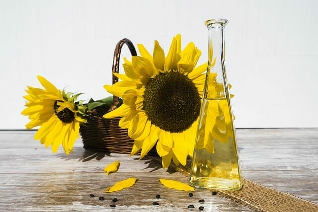  Ein Flakon mit Öl neben Sonnenblumen