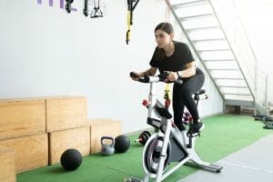  Frau trainiert auf einem stationären Fahrrad