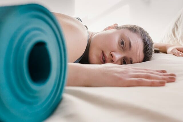  Frau erschöpft vom Training, neben der Trainingsmatte