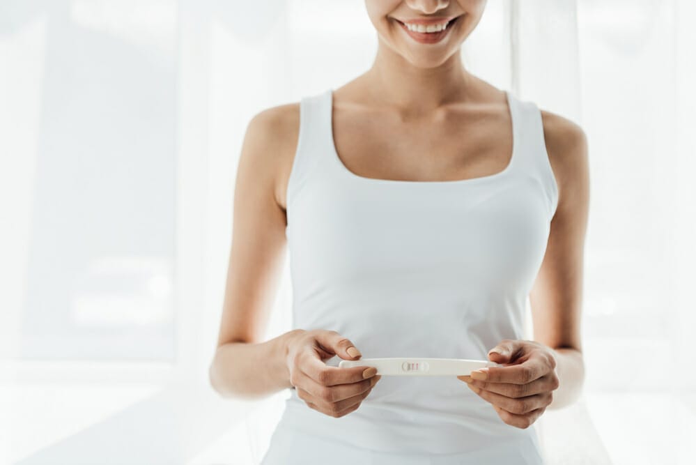  eine zufriedene Frau hält einen positiven Schwangerschaftstest