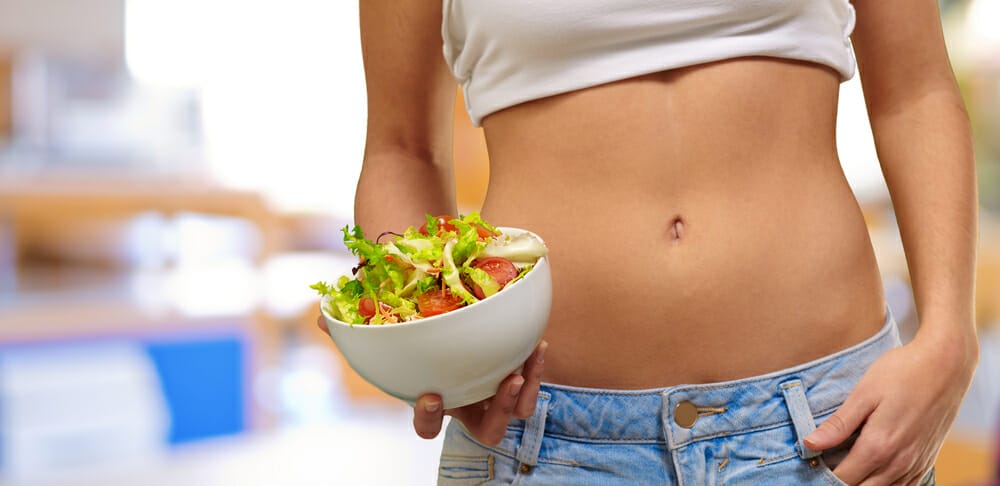  eine schlanke Frau hält eine Salatschüssel mit Gemüse